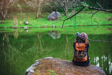 Young women travel to see nature in winter. She sat on the waterfront rocks at the park. in summer.Young women travel to see nature in winter. She sat on the waterfront rocks at the park. in summer.