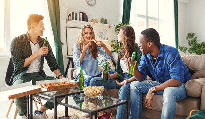 group of happy friends with beer and pizza at home