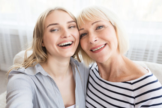 Elderly mother and daughter taking selfie at home