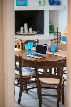 Laptop Standing On Ancient, Vintage And Old Oak Table In Living Room Next To Fireplace With Candles. Fire Is Not Burning. Empty Glasses Of Wine Or Beer. Waiting For Guests. Concept Of Working At Home 