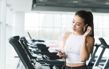 Woman choosing music on smartphone in gym
