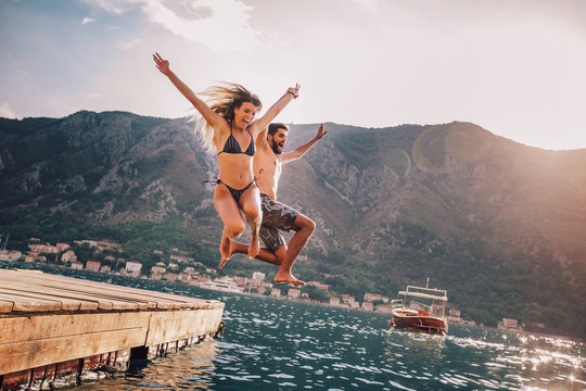 Young couple jumping from a pier into the water