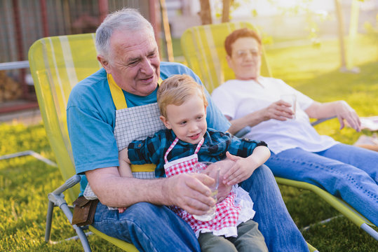 Picture of grandmother and grandfather having fun with their grandson. Sitting in their backyard and smiling.