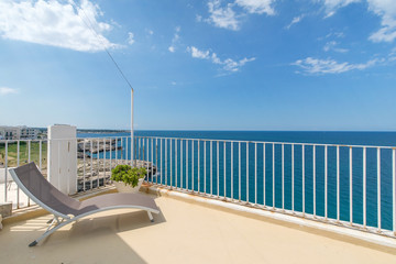 Fototapeta premium Four sunbathing beds layed on a villa roof next to the sea side. Beautiful view of blue sky and clean blue sea. 