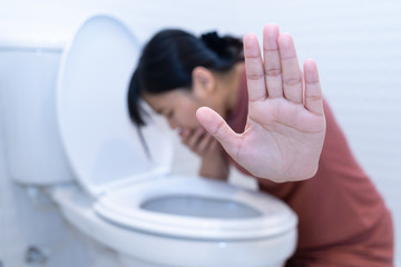 Woman hold hand and vomiting in toilet - sick concept - obrazy, fototapety, plakaty
