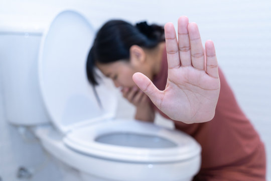 Woman hold hand and vomiting in toilet - sick concept