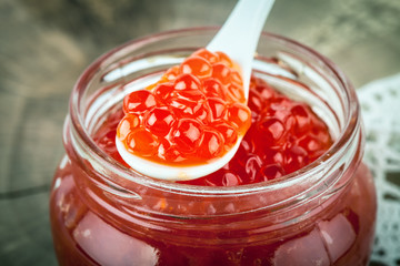 Red caviar in glass jar with spoon . Sea food. Healthy eating. Diet. Wooden background in the style of Shabby Chic.