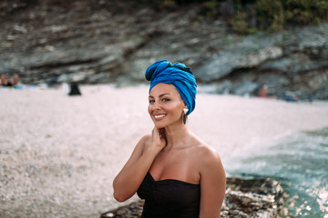 Outdoor portrait of beautiful woman with headscarf enjoying on the rocky beach.