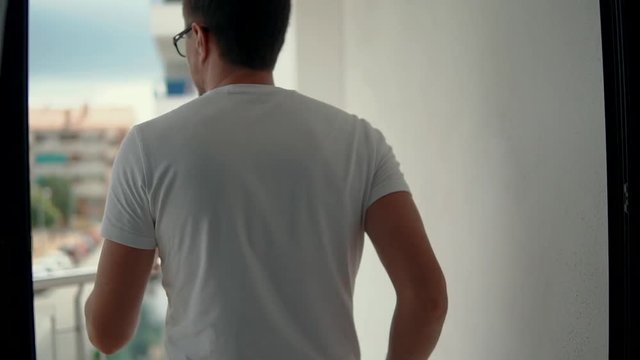 Man goes on balcony.