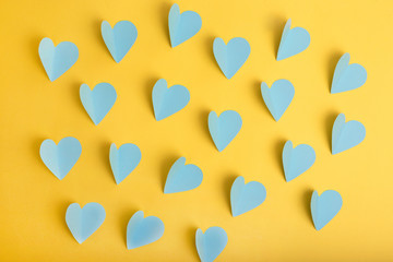 Blue paper hearts on yellow background. Flat lay. Top view