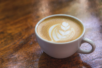 white coffee mug.  Coffee is a latte. table on the wooden table in vintage style, taken from the top view, see the froth of milk foam.