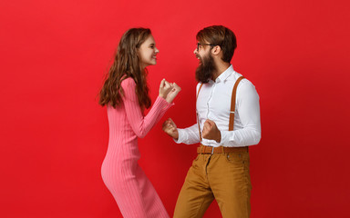 young happy couple won emotionally celebrating win on colored red background.