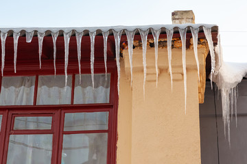 Icicles hang from the snow-covered roof of a building.
