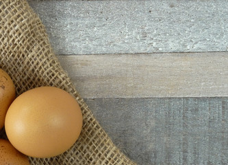 Brown chicken eggs on burlap over wooden background
