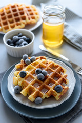 Belgian waffles with blueberries and honey on gray wooden background. Homemade healthy breakfast. Selective focus