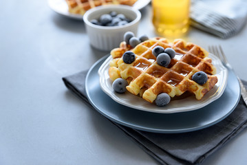 Belgian waffles with blueberries and honey on gray wooden background. Homemade healthy breakfast....
