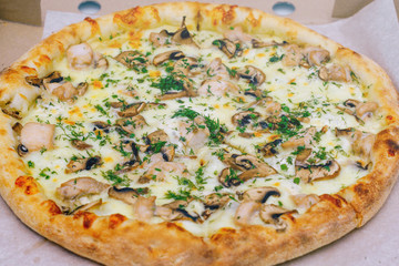 Pizza in a cardboard box on a light background. Top view. Pizza delivery. Pizza menu. Pizza on the kitchen table.