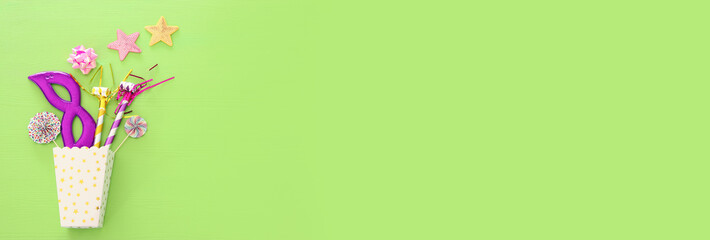 carnival party celebration concept with mask and colorful party accessories over green wooden background. Top view. Flat lay.