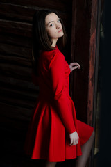 beautiful young slim woman dressed in a bright red dress with a skirt. Poses for a photo in an old-fashioned room with an old decor