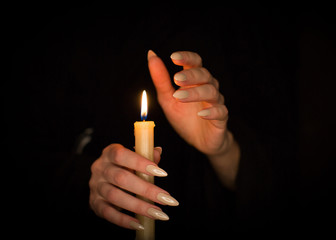 Candle and female witch hands with sharp pearl nails. Divination and witchcraft, low key.