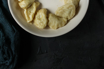 dumplings in a white plate (stuffing dough, different fillings). food background. dark background. top