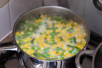 boiling corn with peas in pot