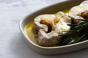 boiled fish with olive oil and rosemary in dish