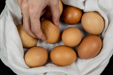 Closeup of a female hand picking fresh egg from a white cloth on a tabletop