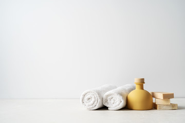 Fototapeta na wymiar Spa concept: beautiful ceramic bottle, handmade organic soap, white towels and on concrete light surface with copy space.