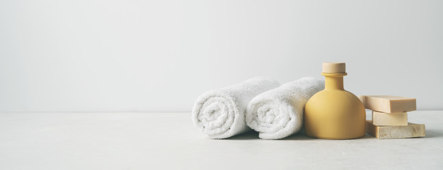 Spa concept: beautiful ceramic bottle, handmade organic soap, white towels and on concrete light...