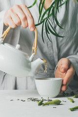 Female hands pouring tea from teapot to teacup selective focus. Brewing and Drinking tea.