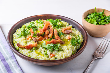 Traditional Italian risotto with peas, carrots and fried bacon, pancetta in rustic style, close-up