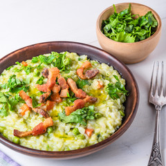 Traditional Italian risotto with peas, carrots and fried bacon, pancetta in rustic style, close-up