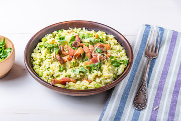 Traditional Italian risotto with peas, carrots and fried bacon, pancetta in rustic style, close-up