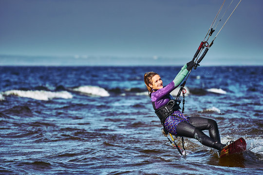 A female kiter slides on the surface of the water. Splashes of water fly apart. Close-up.