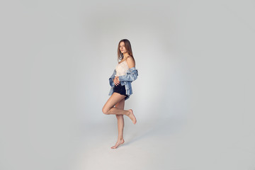 beautiful young woman in denim shorts and shirt posing in the studio on a white backgroun