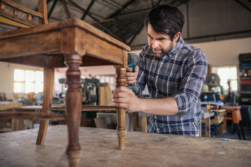 Woodworker screwing together a chair in his carpentry workshop