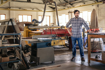 Woodworker leaning on a table in his large workshop
