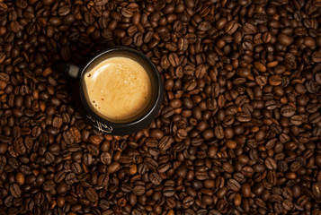 A cup of black coffee with milk standing on coffee beans. A healthy breakfast concept.