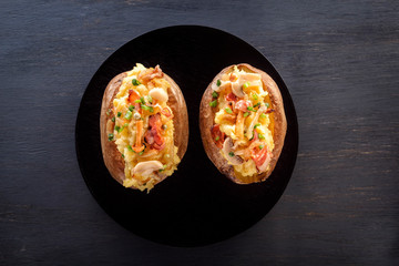 Baked potatoes with bacon and mushrooms in a rustic way on a wooden board. Close-up. Copy space. Top view