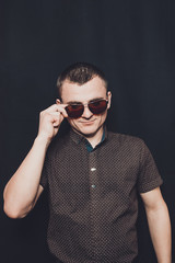 portrait of a sexy man dressed in a black shirt and brown sunglasses