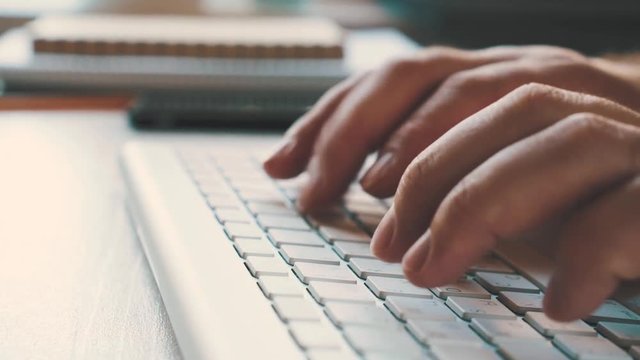 Male hands typing on the wireless keyboard. Workplace of businessman in the office. Close view and very smooth dolly shot 4K video