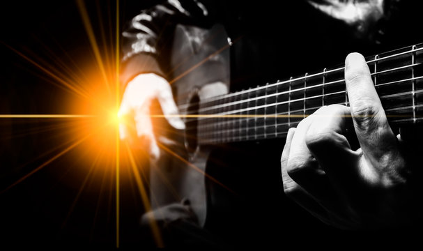 closeup male artist hands playing acoustic guitar on stage with concert light