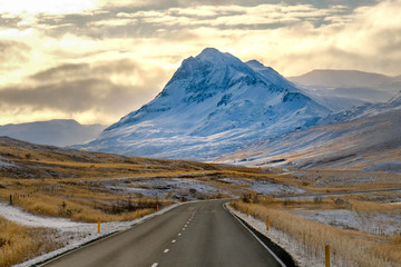 Long road curve in iceland with snow mounrtain background. afternoon time gold cloud