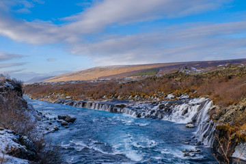 Hraunfossar waterfall in cloudy day with snow on grass beautiful landscape