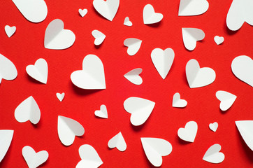 Valentine's day romantic background. White paper hearts at red backdrop, top view.