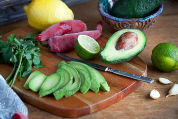 cooking mexican food  guacamole - avocado, lime, lemon, pepper, garlic and cilantro on a wood table