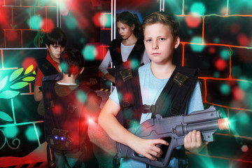 Fototapeta na wymiar teen boy standing with laser pistol in dark lasertag room