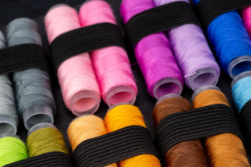 Group of colorful spools of thread used to sewing, needlework and embroidery over bright yellow background