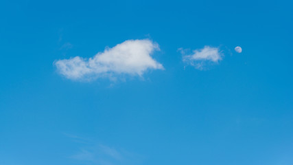 Moon on the daylight blue sky with clouds